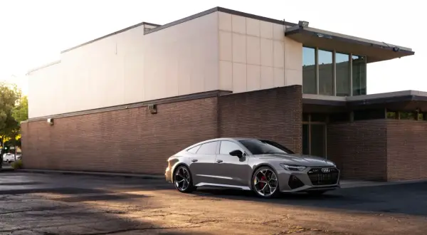 Elegancki, szary Audi RS7 zaparkowany przed nowoczesnym budynkiem.