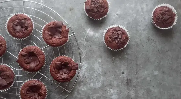 Pyszne babeczki brownie, udekorowane kawałkami czekolady, stygną na kratce.