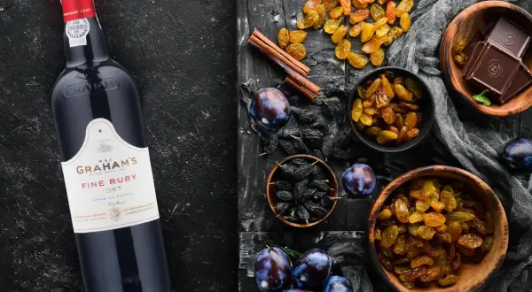 Butelka Graham's Fine Ruby Port obok bakalii: rodzynek, śliwek, czekolady i cynamonu. Idealny do deserów, porto ile procent?