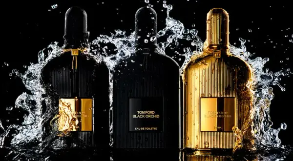 Trzy flakony perfum Tom Ford Black Orchid, w tym jeden złoty, otoczone wodnymi rozpryskami. Wyczuwalna nuta wanilii.