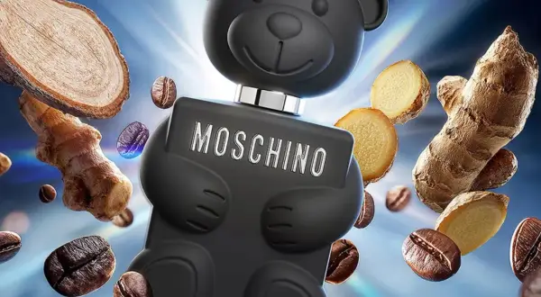 Czarny flakon Moschino Toy Boy w kształcie misia otoczony ziarnami kawy i imbirem.