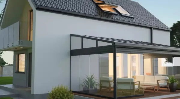 Modernes Haus mit Glas-Wintergarten, der zum **Wintergarten selber bauen** einlädt. Gemütliche Sitzmöbel laden zum Verweilen ein.