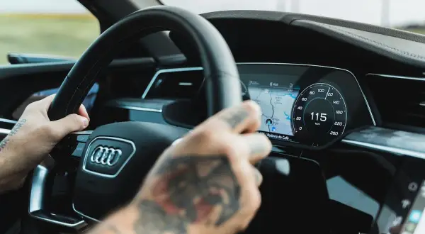 Ręce na kierownicy Audi A9, cyfrowy kokpit pokazuje 115 km/h.