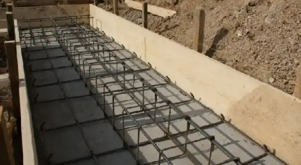 Siatka zbrojeniowa w drewnianej formie, gotowa na betonowanie. Widać, ile zbrojenia na fundamenty potrzeba do solidnej konstrukcji.