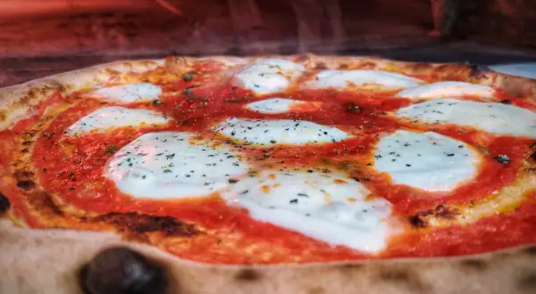 Gorąca pizza z ciągnącym się serem i sosem pomidorowym. Czy pizza jest ciężkostrawna? Zależy od składników i sposobu przygotowania.
