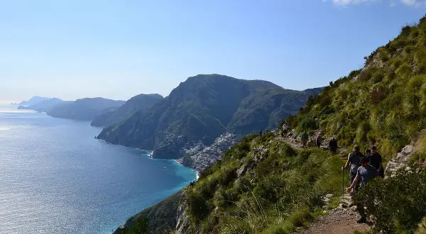 Escursionisti sul Sentiero degli Dei, con vista mozzafiato sulla costa amalfitana e il mare blu intenso.