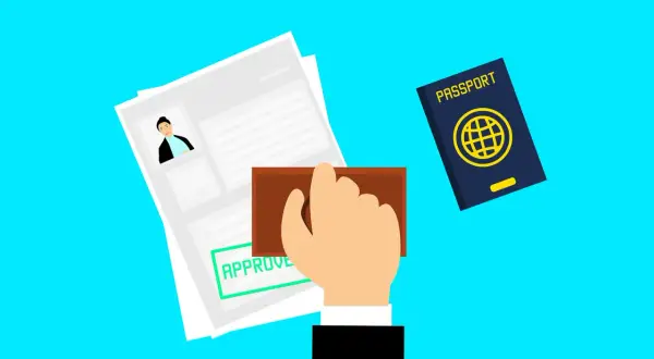 Ręka z pieczątką "APPROVE" nad dokumentem, obok paszport. Czy Albania jest w Schengen? To pytanie podróżnych.