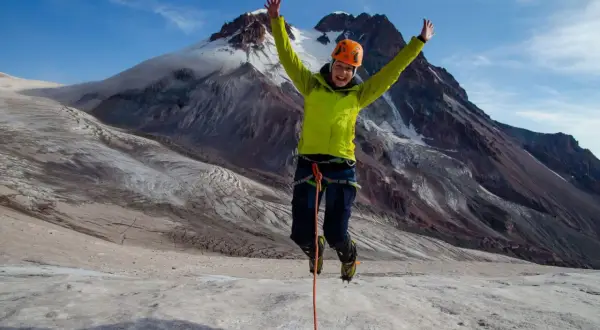 Radosny alpinista skacze na lodowcu pod Kazbekiem w Gruzji.