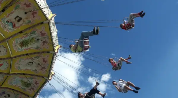 Flugkarussell auf dem Volksfest Gmund. Menschen schweben im Himmel, die bunte Kirmes dreht sich.