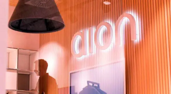 Jasne, oto propozycja:

Logo Aion Bank S.A. świeci na pomarańczowej ścianie. W tle widać cień postaci i regały.