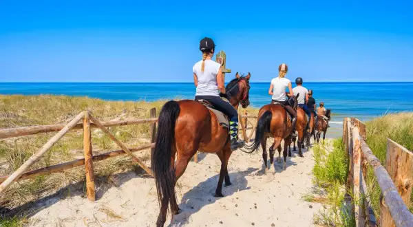 Jazda konna po piaszczystej plaży nad błękitnym morzem.