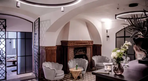 Eleganckie fotele SPA, kominek i bukiet kwiatów w przytulnym wnętrzu.