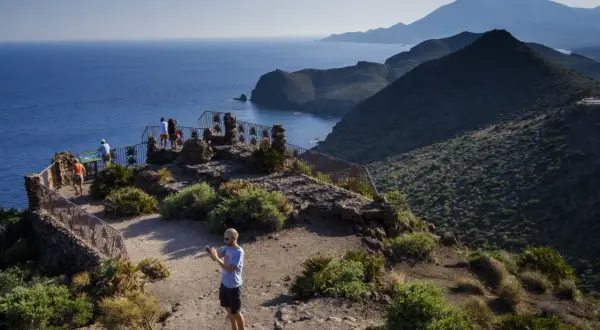 Mirador en Cabo de Gata-Níjar con vistas al mar azul y montañas. Turistas disfrutan del paisaje.
