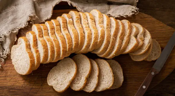 Czerstwy chleb pokrojony w kromki na desce. Świetny pomysł, co zrobić z czerstwego chleba, to grzanki lub bułka tarta.