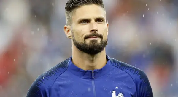 Olivier Giroud w deszczu, z charakterystycznymi fryzurami piłkarskimi i zarostem.