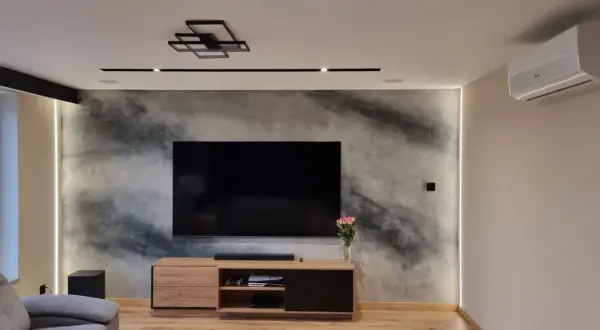 Nowoczesny salon z telewizorem na tle ściany z efektem betonu, jak zrobić tynk dekoracyjny.