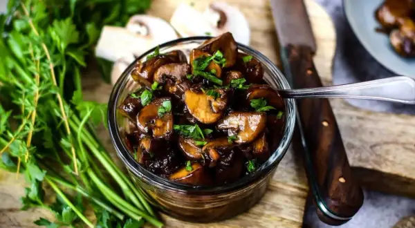 Schmackhafte Champignons in dunkler Sauce, garniert mit Petersilie. Perfekt für Ihre nächsten Champignons Rezepte.