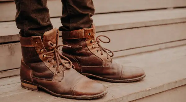 Brązowe, sznurowane buty na drewnianych schodach. Idealne do ozonowania butów, by odświeżyć je po długim dniu.