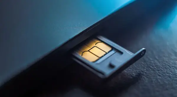 Złota karta SIM w wysuwanej tacce telefonu. Numer karty SIM jest kluczem do łączności.