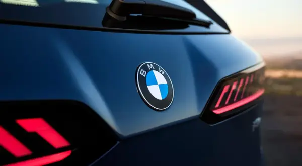 Nowe znaczki samochodowe BMW błyszczą na ciemnoniebieskim lakierze. Widoczne są charakterystyczne tylne światła.