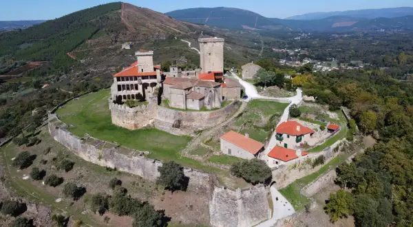 El imponente castillo de Monterrey se alza sobre una colina, rodeado de murallas de piedra y un paisaje verde.