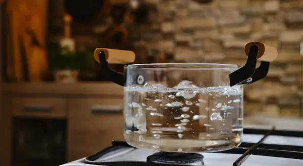 Comment avoir de l'eau chaude sans chauffe eau : une casserole en verre bout sur une cuisinière à gaz.