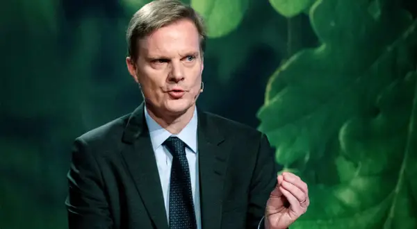 Jens Henriksson, VD för Swedbank, talar med en gest. Bakgrunden är grön med stora blad.
