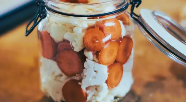 Ein Glas mit Karottenscheiben und Blumenkohl, bereit zum Blumenkohl fermentieren.