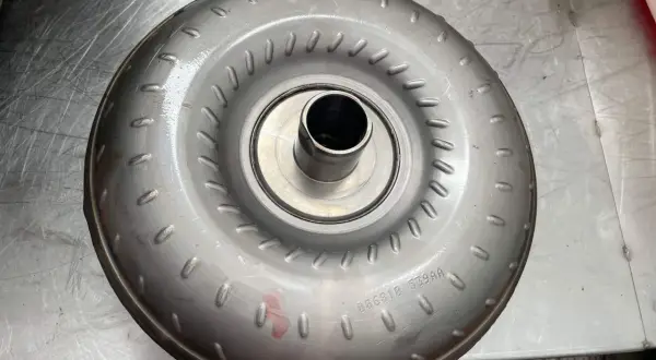 Metalowy konwerter momentu obrotowego, jeden z rodzajów sprzęgieł, leży na metalowej powierzchni.