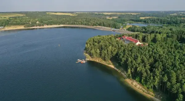 Zalew Chańcza otoczony lasem, z hotelem i pomostem.