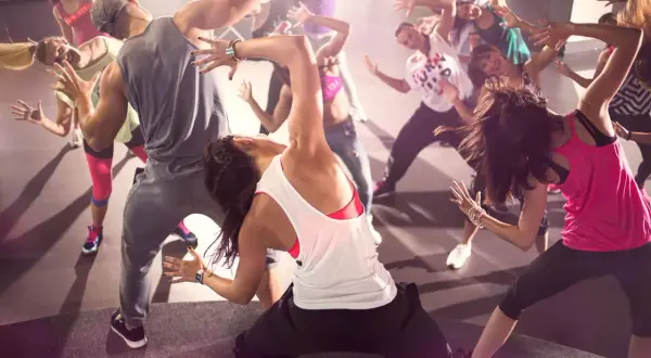 Un gruppo di persone balla con energia durante una lezione di Zumba. Movimento e divertimento per chi vuole che zumba fa dimagrire.