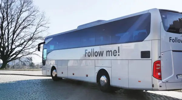 Autokar z napisem "Follow me!" czeka na pasażerów przy lotnisku w Koszalinie.