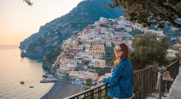 Kobieta podziwia malownicze miasta we Włoszech, Positano, z widokiem na morze i kolorowe domy wznoszące się po zboczu góry.