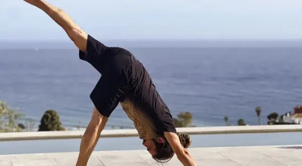 Hombre en postura de perro boca abajo, practicando yoga flow que es una secuencia fluida de posturas.