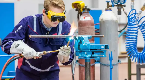 Ein junger Mann schweißt Rohre, eine praktische Übung für Weiterbildungsmöglichkeiten als Anlagenmechaniker SHK.