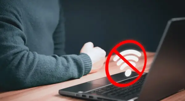 Laptop nie widzi wifi. Czerwony okrąg z przekreślonym symbolem wifi nad klawiaturą sugeruje problem z połączeniem internetowym.