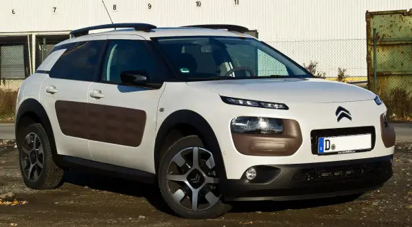 Biały Citroen Cactus z brązowymi wstawkami Airbump na drzwiach, zaparkowany na brudnym podjeździe.