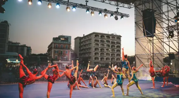 Atleti in posa sul palco di Riccione, un'esibizione di ginnastica ritmica che incanta il pubblico.