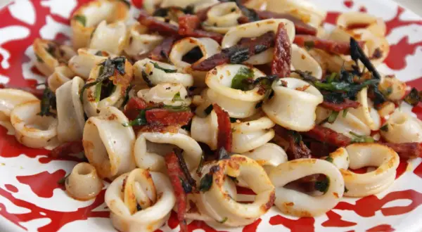 Anneaux de calamar et chorizo grillés à la plancha, parsemés d'herbes fraîches. Un délice croustillant et savoureux.