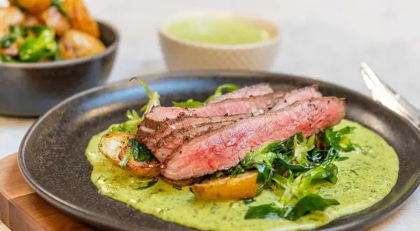 Skivad flankstek med perfekt flankstek temp, serverad med rostade potatisar och en krämig örtsås.