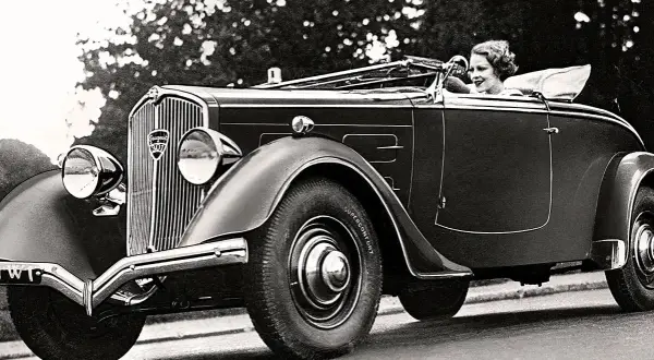 En kvinna kör en elegant cabriolet, ett exempel på gamla bilmodeller från 1930-talet.