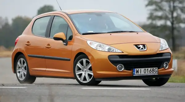 Pomarańczowy Peugeot 207 1.6 HDi na drodze.