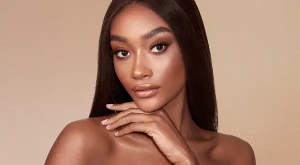 Modella con pelle scura e capelli lisci, evidenziando la differenza tra bronzer e contouring per scolpire il viso.