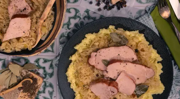 Kassler in Sauerkraut mitkochen wie lange? Zartes Kassler auf Sauerkraut mit Kartoffelpüree, garniert mit Lorbeerblättern und Kümmel.