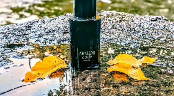 Elegancki flakon Armani Code Parfum 125ml, otoczony jesiennymi liśćmi i wodą, emanuje luksusem.