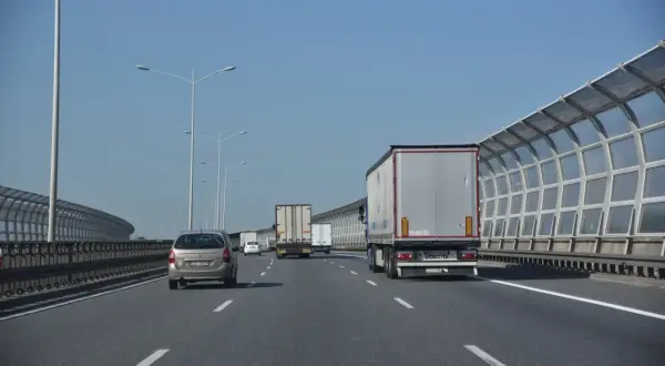 Jadę lewym pasem autostrady za ciężarówką. W oddali widać inne pojazdy i ekrany akustyczne.