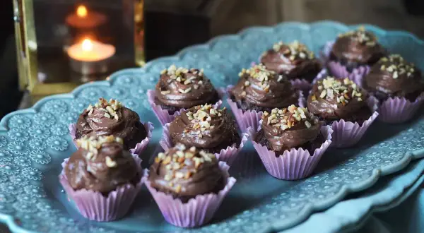 Mini cupcakes choklad med krämig frosting och hackade nötter, serverade på ett vackert fat.