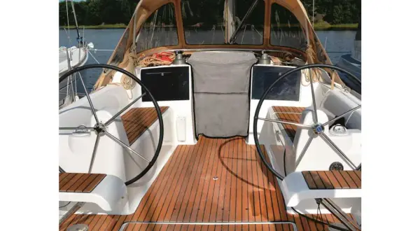 Il ponte di uno yacht con due timoni, un tendalino e un boccaporto, pronto per la navigazione.