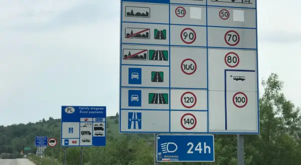 Znaki drogowe informujące o różnych rodzajach dróg, opłatach i ograniczeniach prędkości. Wskazują na różne rodzaje pojazdów i dopuszczalne prędkości na poszczególnych odcinkach.