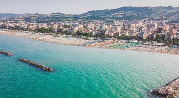 Vista aerea di San Benedetto del Tronto, con il suo lungomare affollato di ombrelloni colorati e il mare turchese.